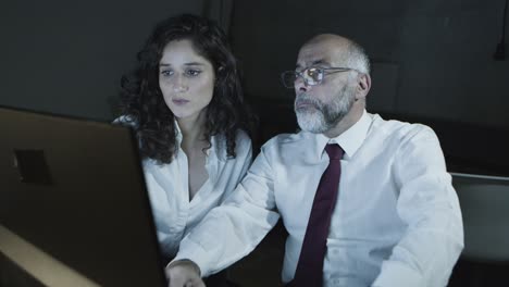 Businessman-pointing-at-computer-and-talking-with-businesswoman
